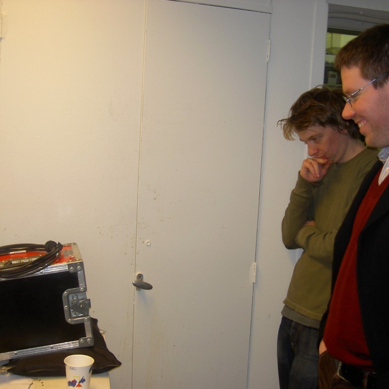 Baddi Z leikstjóri og Auðjón fylgjast með á skjá upptöku af Smørrebrød-atriði.